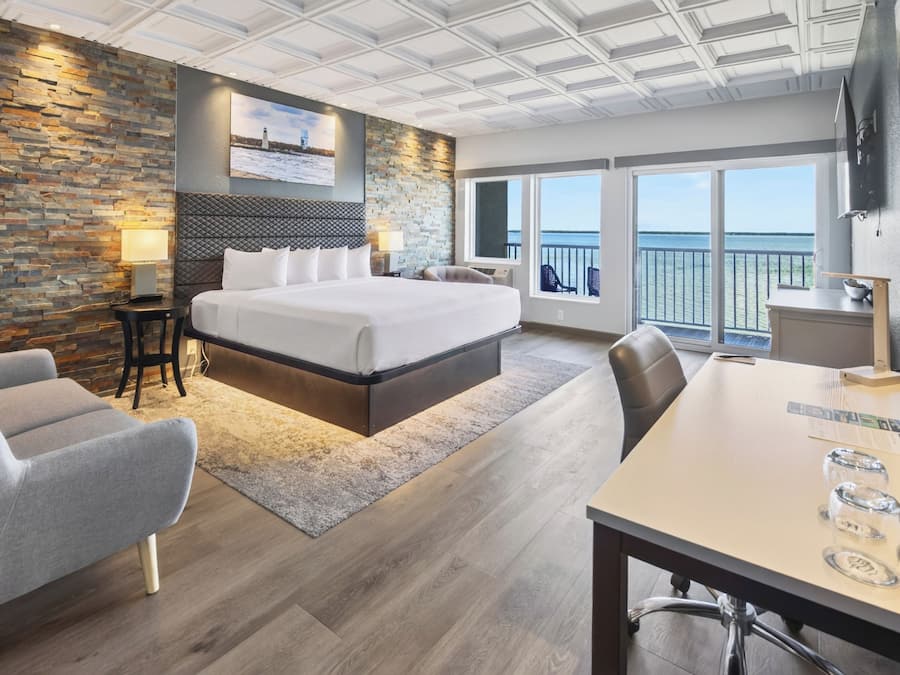Habitació d'hotel amb un llit gran, una taula de treball, una cadira, un televisor i un balcó amb vista al mar.
