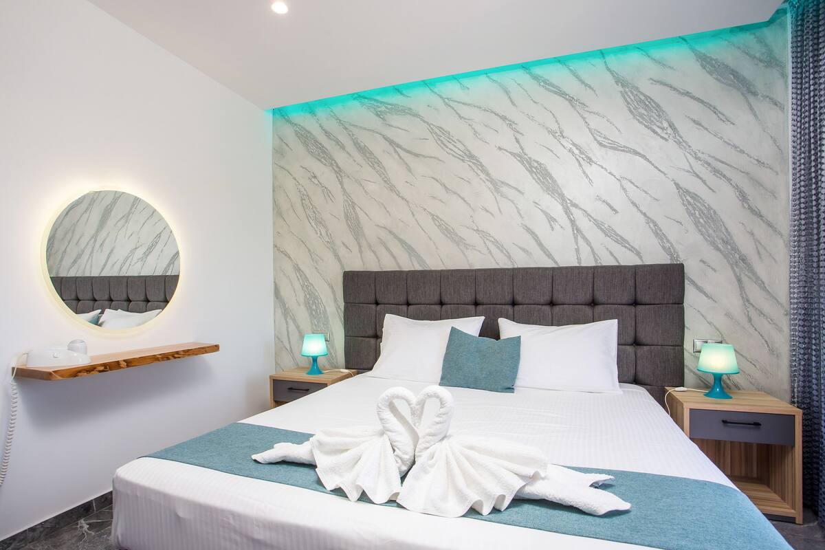 Ein Hotelzimmer mit einem großen Bett, einem runden Spiegel, zwei Nachttischen mit Lampen und einer Wand mit Marmoroptik.