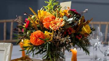A table set with a floral centerpiece, a candle, a pumpkin, and wine glasses.