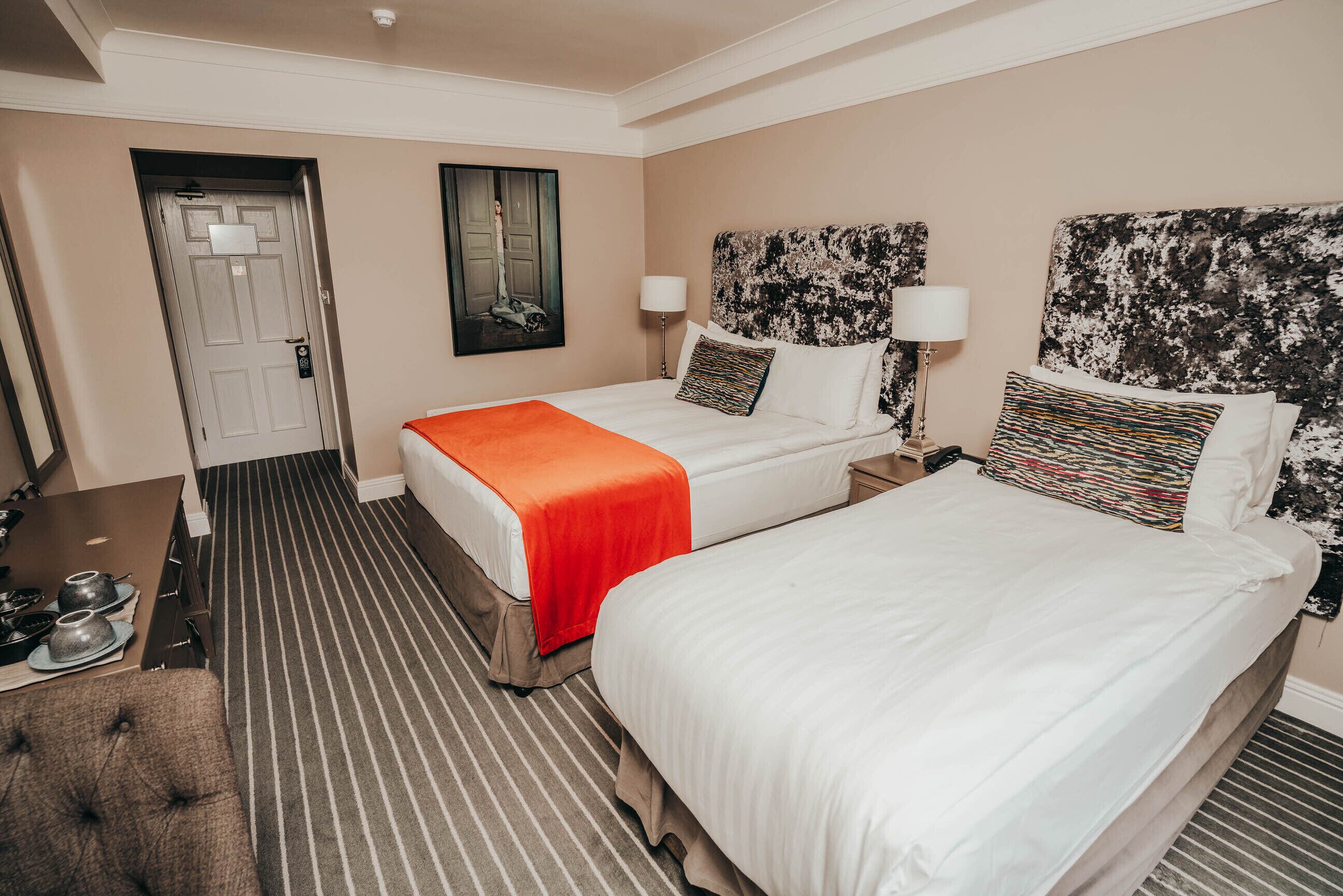 Una habitación de hotel con dos camas, un escritorio y una puerta.