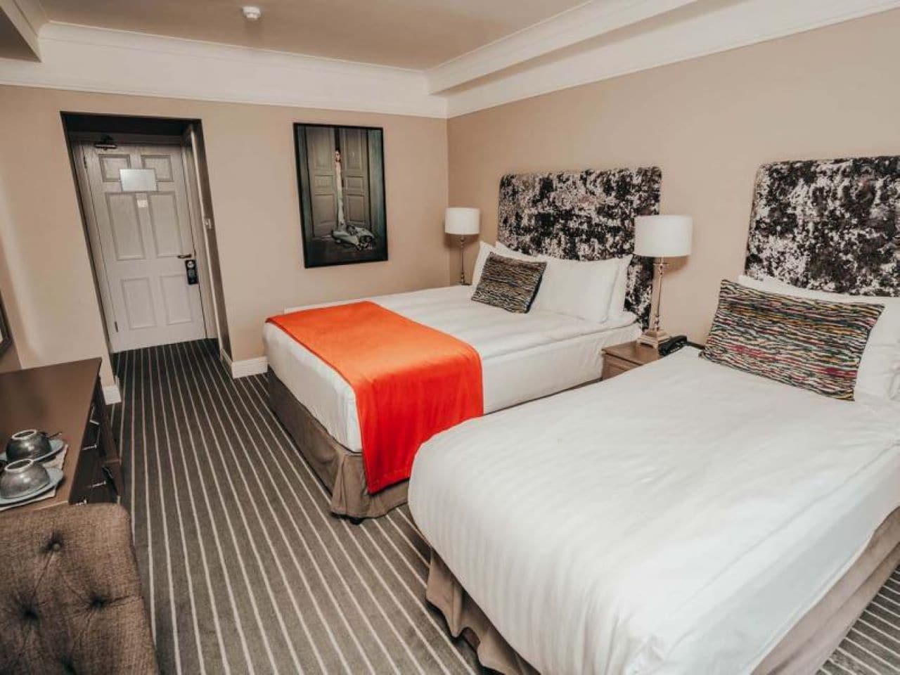 A hotel room with two beds, a desk, and a chair.