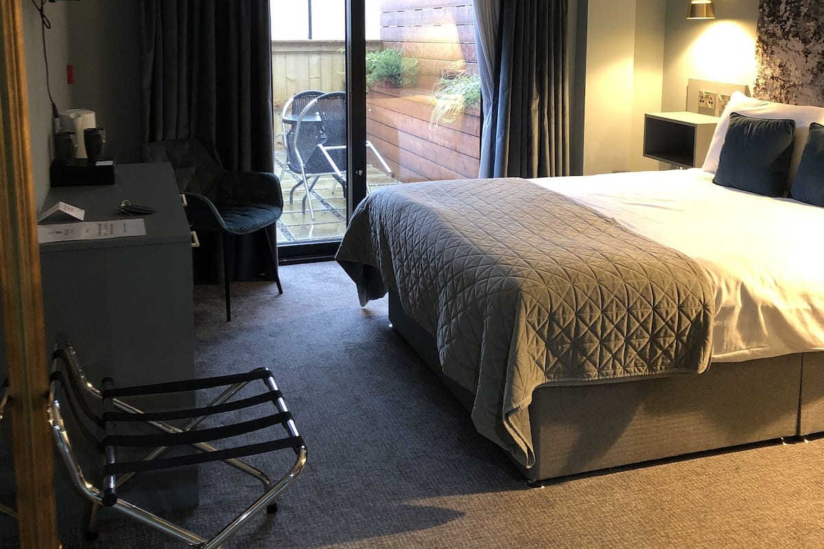 Ein Hotelzimmer mit Bett, Schreibtisch, Stuhl, Fernseher und einem Balkon mit Ausblick.