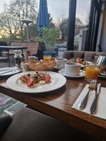 A breakfast table with waffles, fruit, and orange juice.