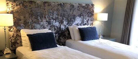 A hotel room with two beds, a large headboard, and a striped carpet.