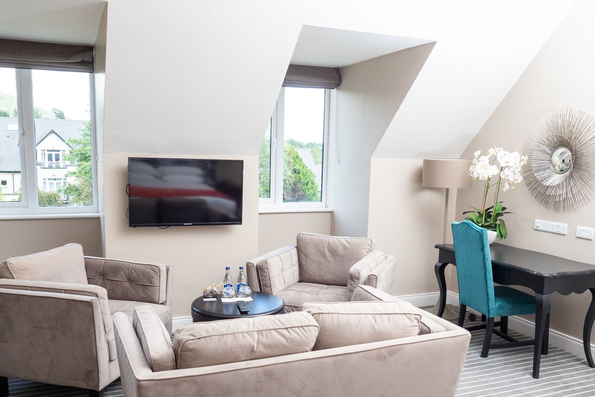 A modern living room with a flat-screen TV, a sofa, a coffee table, and a desk with a chair.
