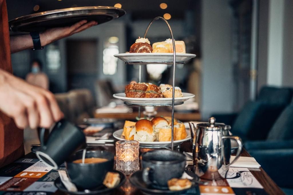 Una bandeja escalonada con pasteles y una cafetera sobre una mesa.