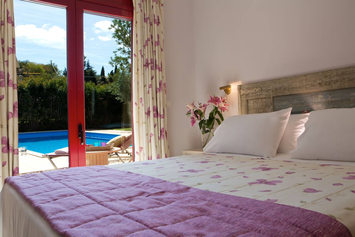 A bedroom with a bed, a nightstand, and a view of a swimming pool.