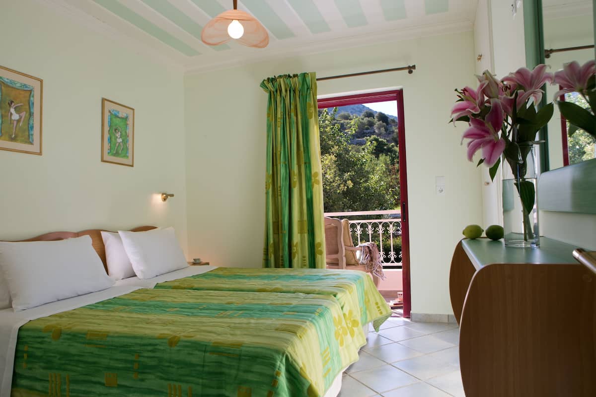 A bedroom with a bed, a desk, a chair, a window with curtains, and a view of the outdoors.