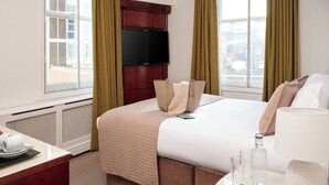 A hotel room with a large bed, a TV mounted on the wall, and a window with curtains. - The Prime London Hotel (London)