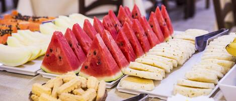 A buffet table with various fruits and pastries.