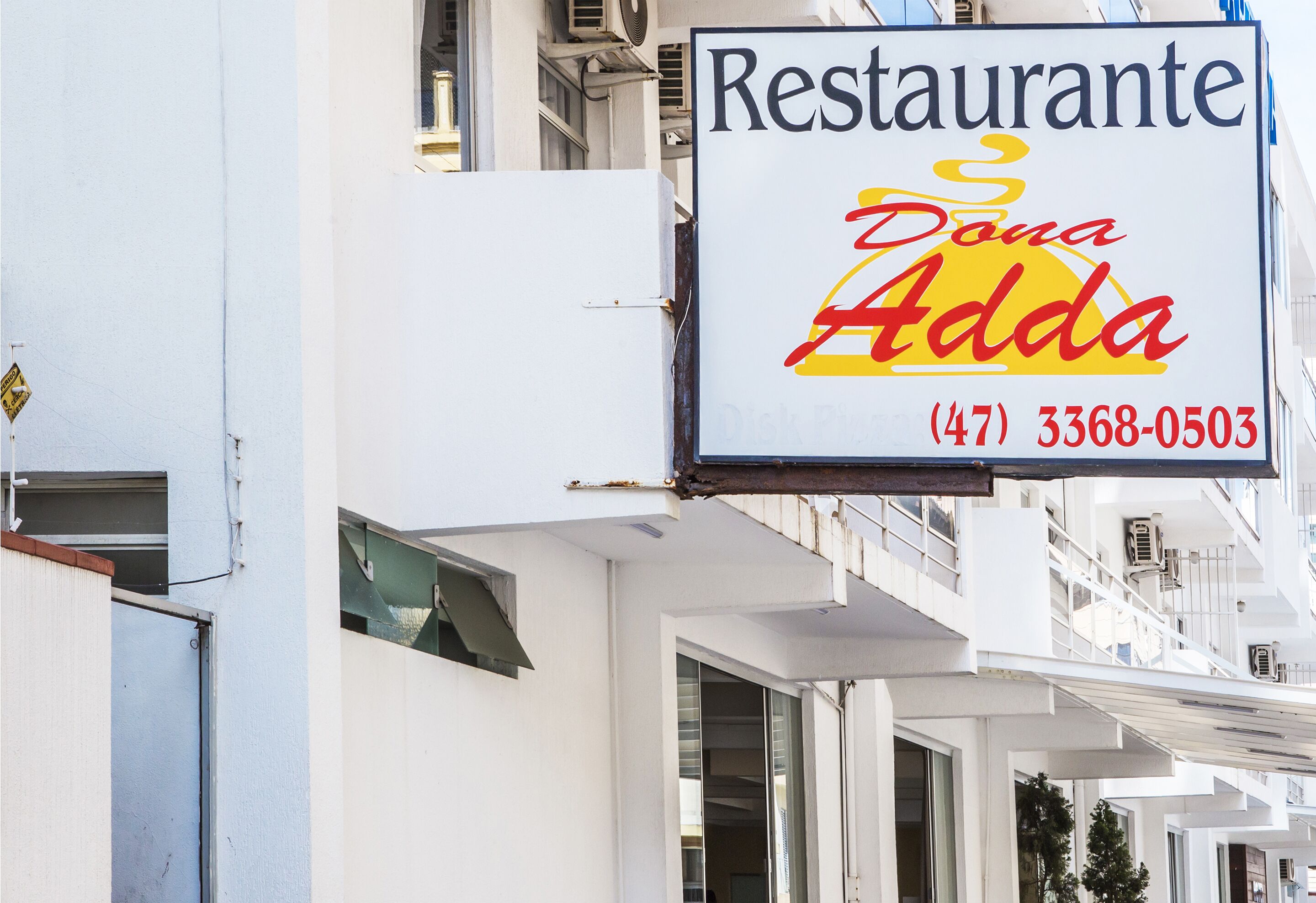 Letrero de restaurante con el nombre 'Restaurante Dona Adda' y un número de teléfono (47) 3368-0503.