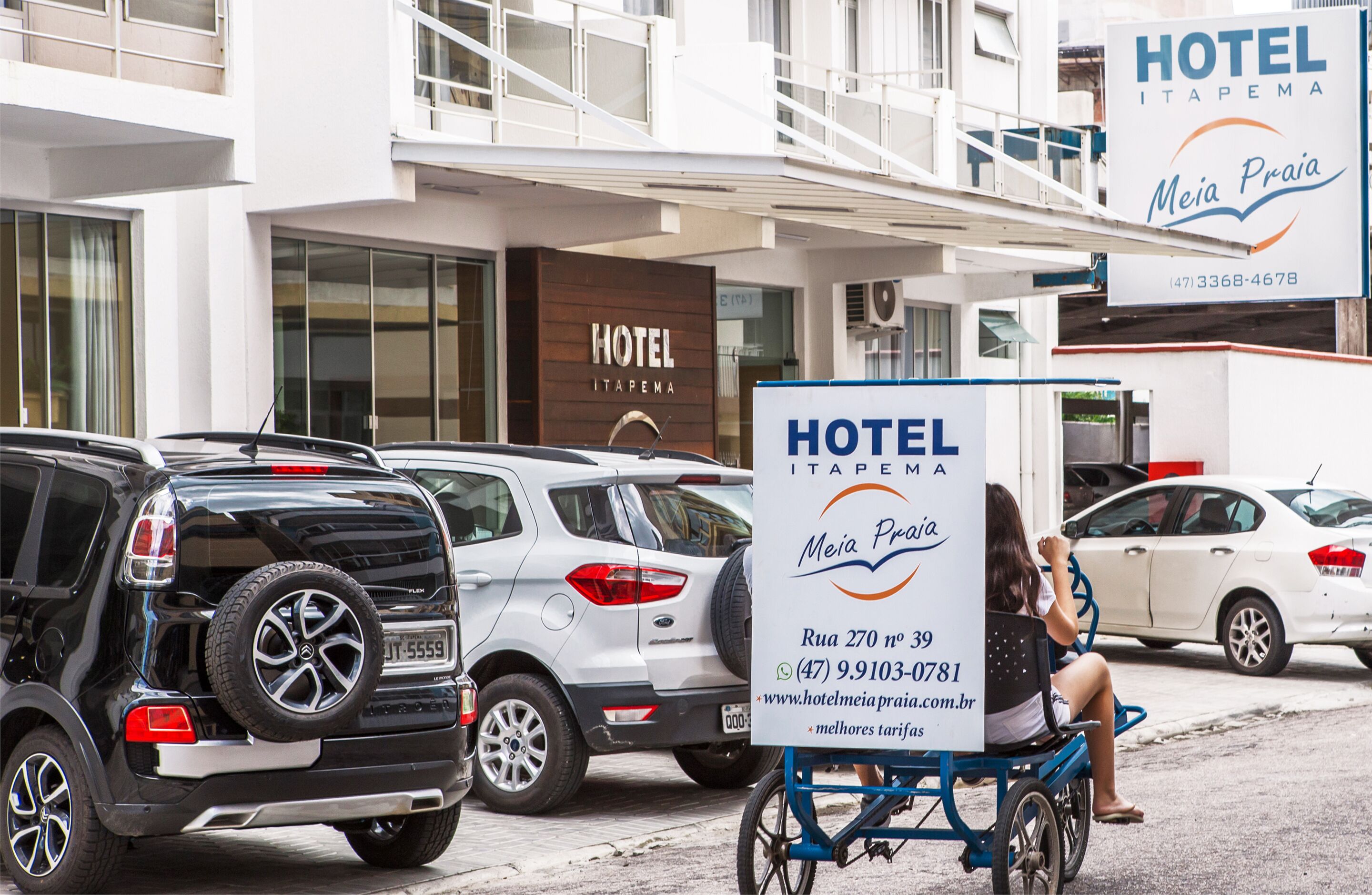 Un hotel llamado "Hotel Itapema" con un cartel que muestra su nombre e información de contacto.