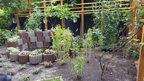 A garden with raised planters, a wooden trellis, and various plants. - Hotel - Restaurant Valley Rose (Vienna)