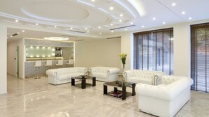 Una sala de estar moderna con un sofá modular, una mesa de centro y un ventanal con persianas.