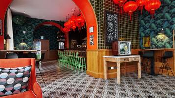 Zona bar con un bancone in legno, sedie verdi e lanterne rosse.