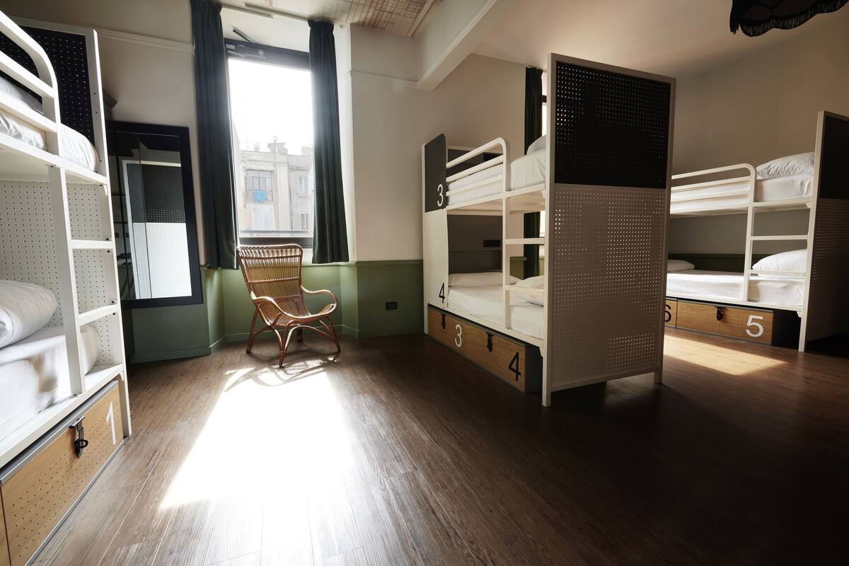 A room with bunk beds, a chair, and a window.