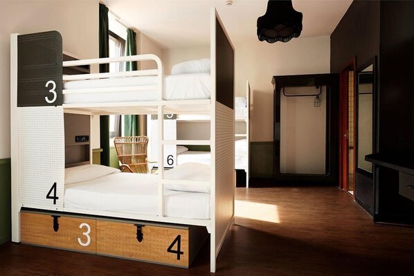 Een stapelbed met de cijfers 3, 4 en 6, een houten ladekast en een klein mandje op het onderste bed.