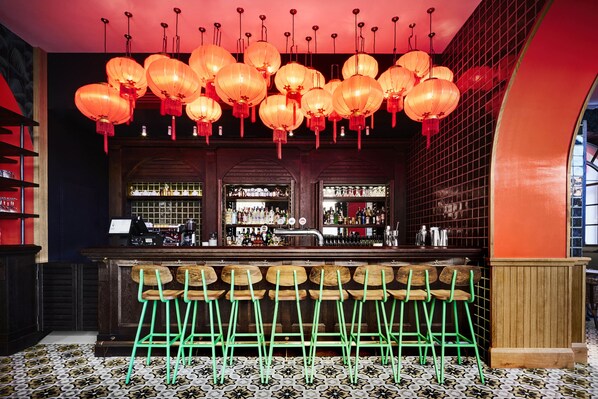 A bar area with multiple stools, a bar counter, and hanging lanterns.