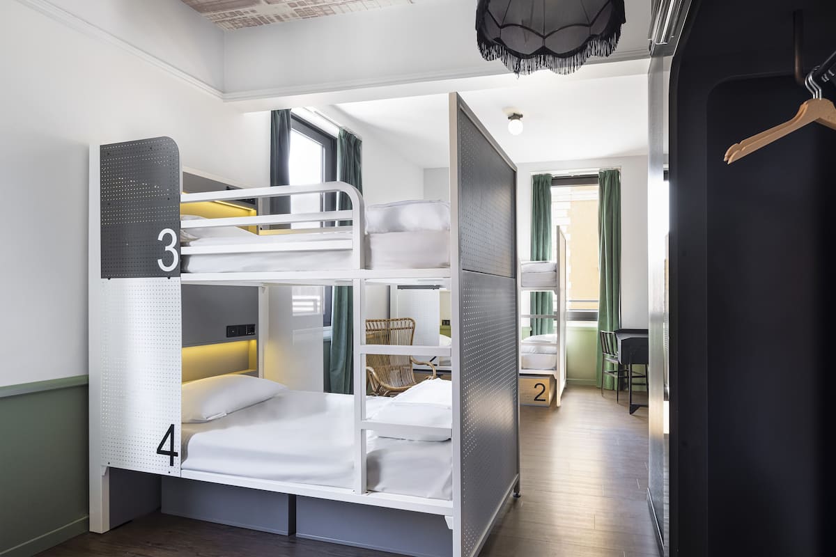 A bunk bed room with a number 3 and 4 bunk, a small table, and a chair.