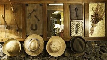 A rustic wall with various items including hats, a wooden door, and a stone wall.