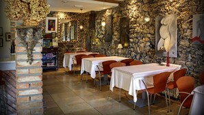 Un restaurant aux murs de pierre, doté de nombreuses tables et de chaises rouges.