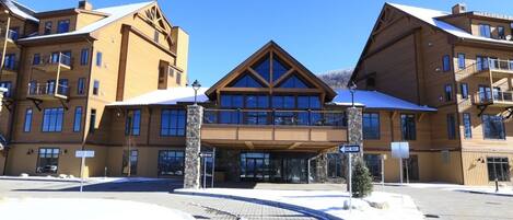 A multi-story hotel with a prominent entrance, balconies, and a clear sky.