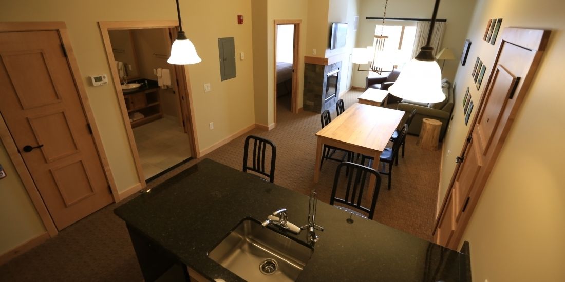 A kitchen with a central island, a dining area with a table and chairs, and a view into the adjacent living room.
