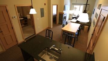 A kitchen with a central island, a dining area with a table and chairs, and a view into the adjacent living room.