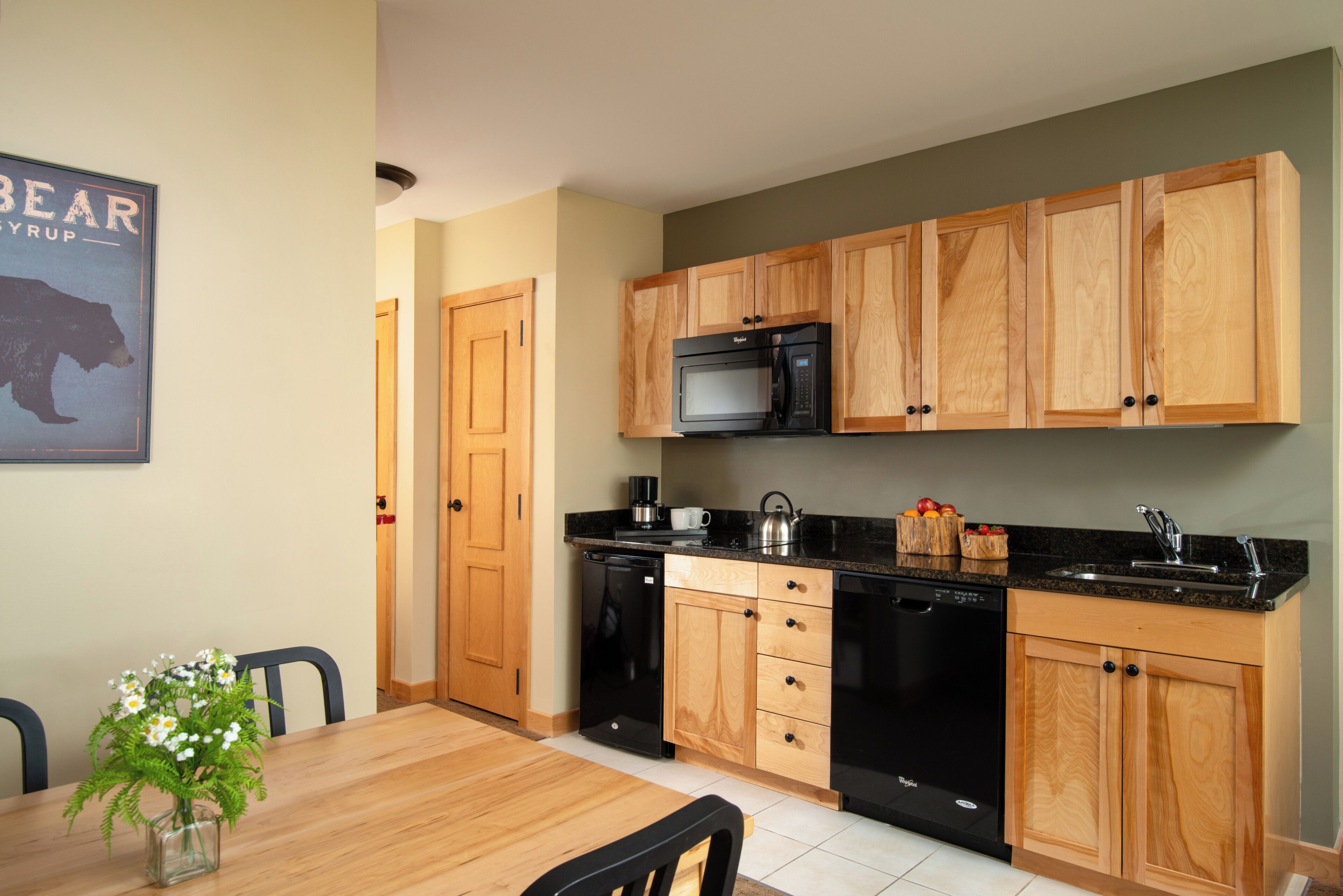 A modern kitchen with wooden cabinets, a built-in microwave, and a coffee maker.