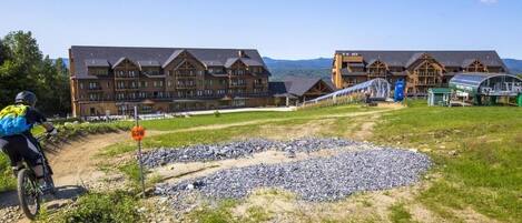 A mountain lodge with a dirt path leading to a building with a 'SLOW' sign.