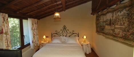Un dormitorio con techo de madera, una cama con ropa de cama blanca, dos lámparas de noche y una ventana con cortinas florales.
