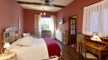 A bedroom with a bed, a desk, a chair, a ceiling fan, and a window with curtains.