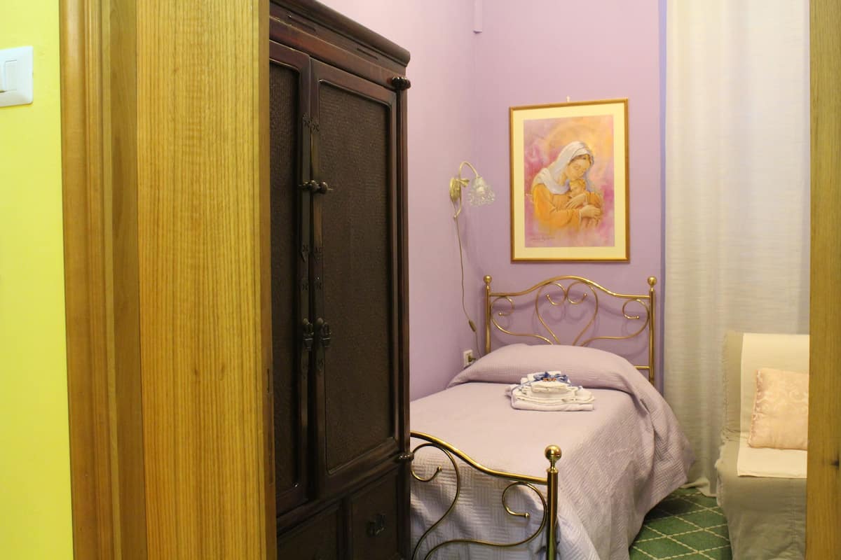 Ein Schlafzimmer mit Bett, Schrank, Gemälde und Stuhl.