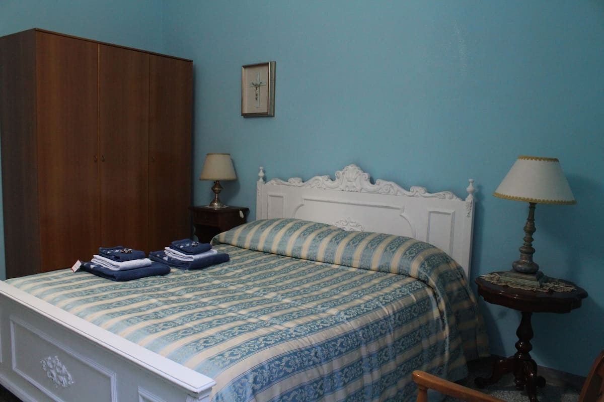 Ein Schlafzimmer mit einem Bett, einem Kleiderschrank, zwei Nachttischen und einer Lampe.