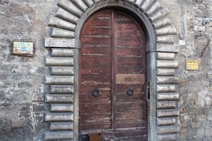 Une grande porte en bois à arc, dotée de poignées métalliques et d’une enseigne au-dessus.