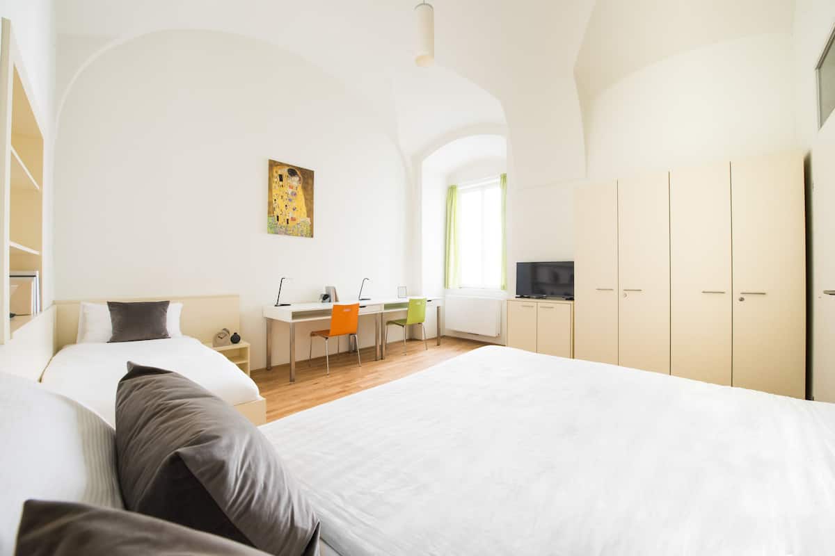 Una camera da letto moderna con un letto grande, una scrivania con due sedie, una televisione e un armadio.
