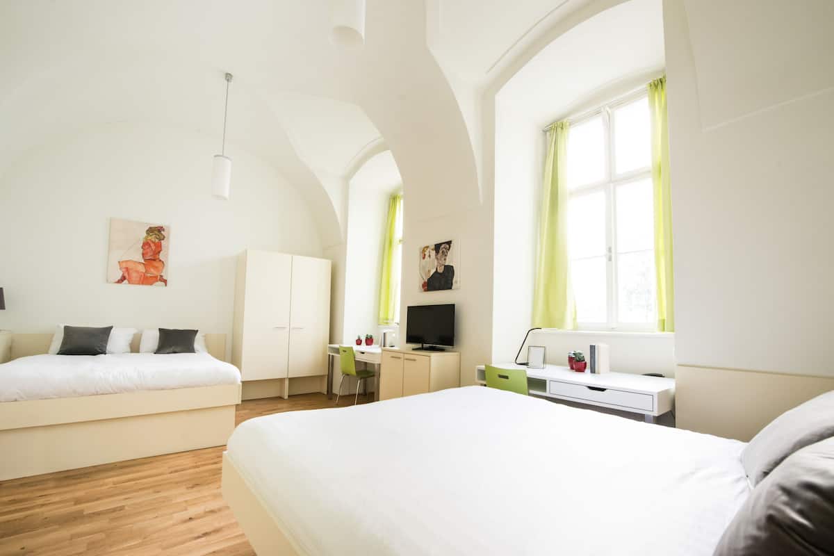 Una moderna camera d'hotel con un grande letto, una scrivania, una sedia e una televisione.
