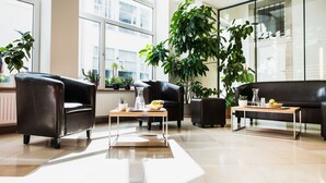Ein stilvolles Wohnzimmer mit Ledersofas, einem Couchtisch und topfpflanzen.