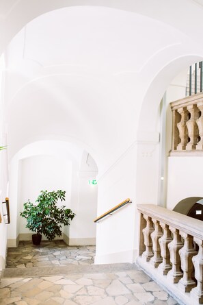 Een trap met stenen treden en een balustrade, die leidt naar een plateau met een bloempot.