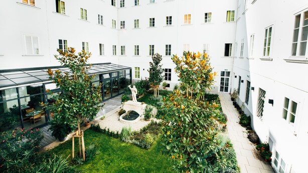 Ein Innenhof mit Wintergarten, einer Statue und verschiedenen Pflanzen.
