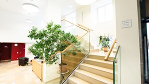 Ein modernes Interieur mit Treppe, Holzgeländer, Glastrennwand und Zimmerpflanzen.
