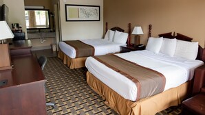 A hotel room with two beds, a desk, a chair, a lamp, and a framed picture on the wall. - Regency Inn (Monroeville)