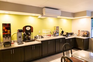 A modern kitchen with a coffee station, microwave, toaster, and a large window.