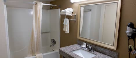 A bathroom with a shower, a sink, a mirror, and a towel rack.