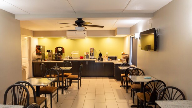A compact kitchen with a dining area, featuring a ceiling fan, a microwave, and a coffee machine. - Regency Inn (Monroeville)