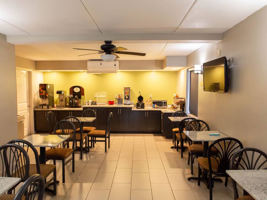 A compact kitchen with a dining area, featuring a ceiling fan, a microwave, and a coffee machine.