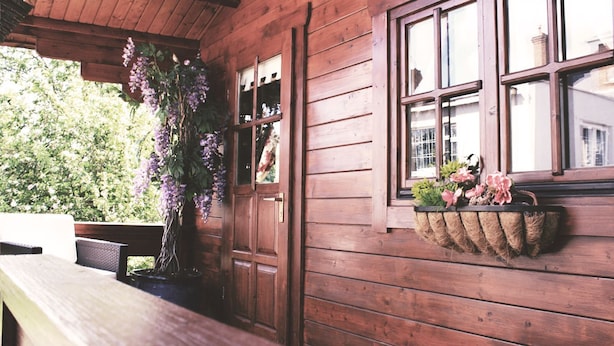 A wooden cabin with a bench and a hanging planter with flowers. - Beaufort House (New Ross)