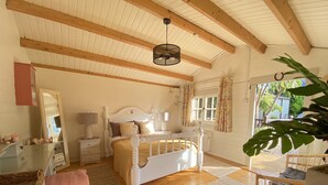 A bedroom with a wooden ceiling, a white bed, a mirror, a dresser, and a window with curtains. - Beaufort House (New Ross)