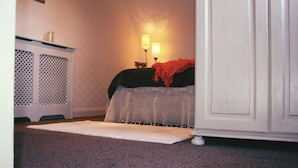 A bedroom with a bed, a nightstand, a lamp, and a carpeted floor. - Beaufort House (New Ross)