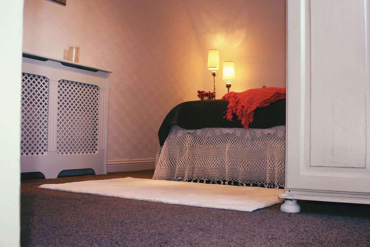 Ein Schlafzimmer mit Bett, Nachttisch, Lampe und Teppichboden.
